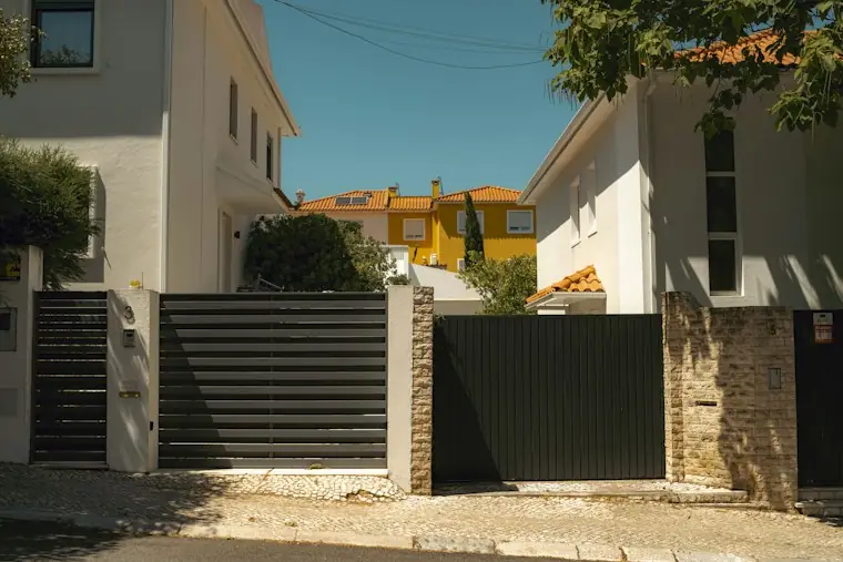 Bahçe Kapısı Modelleri — Beyaz Ege evleri arasında yatay lama demir bahçe kapısı